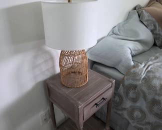 Weathered gray wood nightstand with drawer and rattan cage lamp