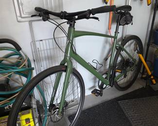 Green hybrid bicycle with flat handlebar, disc brakes and saddle bag