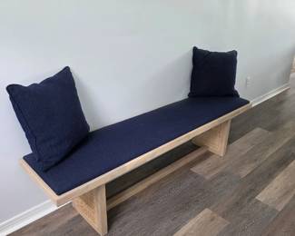 Light wood bench with navy cushion and pair of navy throw pillows