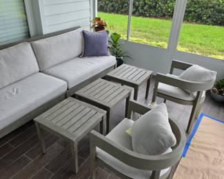 Gray outdoor sectional with slat-top side tables and two armchairs