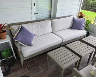 Weathered gray wood outdoor sofa with cream cushions, lavender pillows