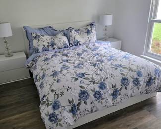 Bed with blue and white floral comforter set and white nightstands