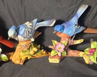 Andrea by Sadek Porcelain Bird Figurines - Cardinal, Blue Jay, Bluebird & Robin Set of four colorful Andrea by Sadek porcelain bird figurines featuring a cardinal, blue jay, bluebird and robin, each perched on a detailed branch with floral or berry accents.  Approx. 4.5"–6.5"H Andrea by Sadek labels/markings Blue Jay and Bluebird marked 9973 Robin has a chipped/broken area; see photos Includes four wooden display bases Market Insight & Estimated Market Value: A charming matched group for bird lovers and Andrea by Sadek collectors, with four popular backyard species represented.  Estimated Market Value: $45–$75