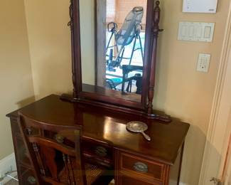 Midcentury mahogany kneehole vanity featuring ornate fretwork scroll mirror with matching cane back chair
