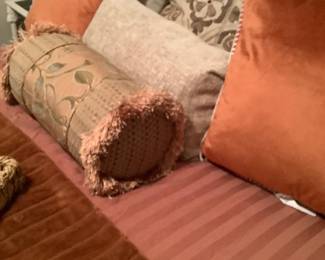 The rust colored pillows on cast iron bed.