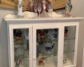 White display cabinet with glass shelves and oriental fan.