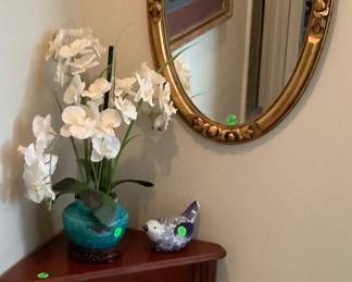 Corner cabinet with drawer and bottom shelf with oval gold mirror above.