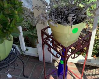 A red stand with live plants in and fall cobalt blue bottle.