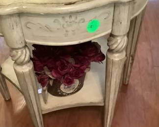 Cream colored round end table with bottom shelf.