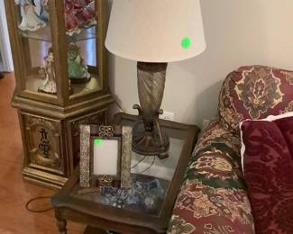 One of the end tables by couch, lighted curio cabinet with glass shelves holding collectible oriental ladies In all  their glory.