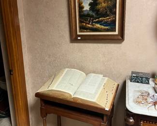 Encyclopedia on a book stand, nice artwork above it 