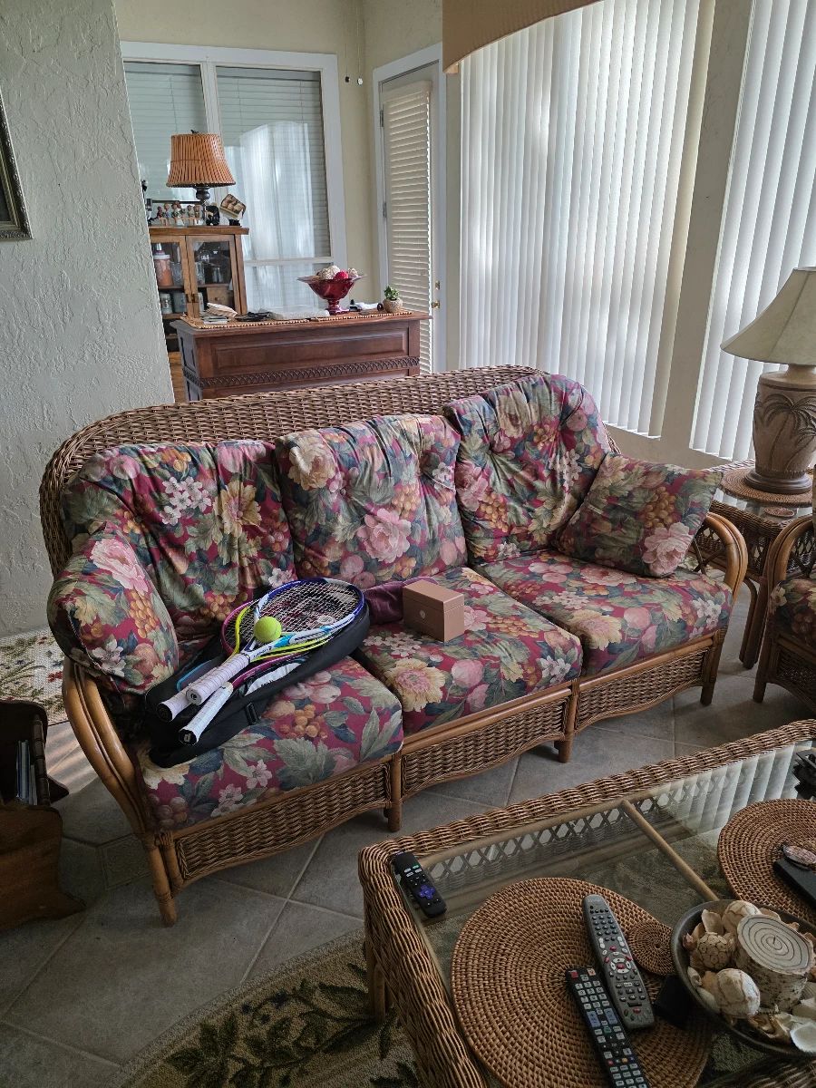 Rattan sunroom sofa set with floral cushions and area rug