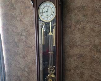 Wall clock with glass case and brass pendulum