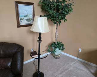 Floor lamp with white shade beside leather chair and framed art