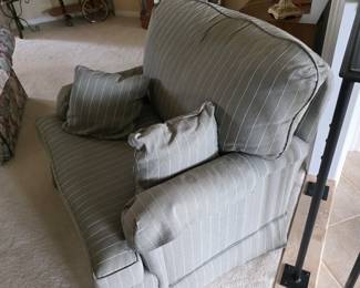 Sage green striped upholstered armchair with accent pillows