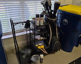 Garage with golf bag, trash bins and yard items