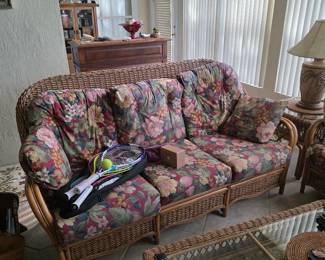 Rattan sunroom sofa set with floral cushions and area rug