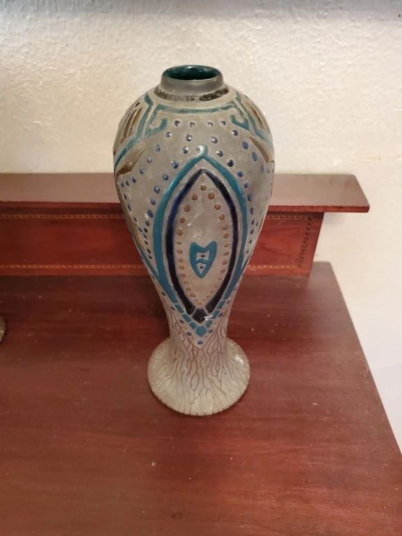 Tall ceramic vase with a cream-colored body and blue geometric Art Deco-style decoration featuring diamond and dot patterns. The vase has a pedestal base and appears to be from the early-to-mid 20th century.