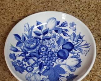 Ceramic plate with blue floral and fruit motif featuring roses, tulips, and berries in a traditional blue and white pattern. The design is centered on a white ground with a rolled rim.