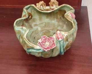 Decorative majolica bowl featuring a scalloped rim with applied floral and leaf details in pink and green glazes. The piece has a naturalistic form with molded botanical elements.