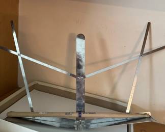 Wooden clothes drying rack with metal frame and multiple horizontal bars for hanging garments. The frame shows age-related wear and patina typical of mid-century household items.