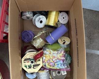 Box containing various spools of thread in multiple colors, embroidery floss, buttons, and other sewing notions and supplies.