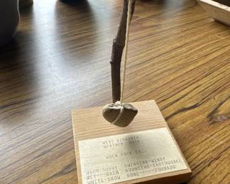 Simple wooden desk organizer with a single pen holder and a small brass or metal cup. The base features printed text and appears to be a vintage office accessory.