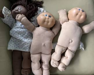 Collection of three vintage doll bodies in various states of completion, including one with dark hair and cloth dress, and two unfinished or partially assembled cloth bodies. Suitable for doll restoration or parts.