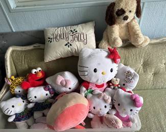 Collection of assorted plush toys including Hello Kitty, Elmo, and other character plushes in various sizes. Mix of vintage and modern stuffed animals suitable for children or collectors.