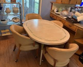 Oval dining table with light wood finish and four matching curved chairs, characteristic of mid-century modern design. The set shows wear consistent with age and use.