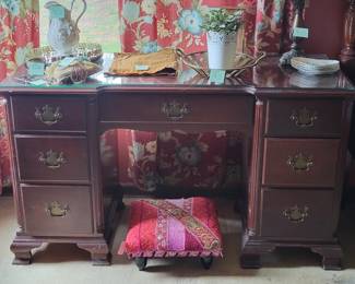 Traditional mahogany desk with a central kneehole and six drawers arranged around it, featuring brass hardware and turned feet. The piece shows good patina consistent with age and use.