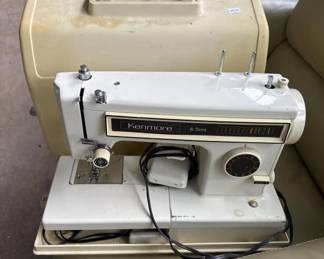 Vintage Sears Kenmore sewing machine with white body and beige carrying case. The machine features a black control panel and appears to be in working condition with its original power cord.