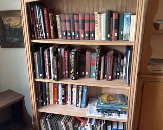 Light wood bookcase with four shelves holding a collection of DVDs, Blu-rays, and other media. The shelves are well-organized with various titles visible.