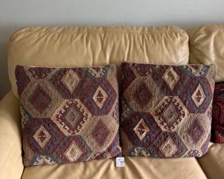Pair of square throw pillows with burgundy and tan geometric diamond pattern. Pillows appear to be in good condition and are displayed on a tan upholstered sofa.