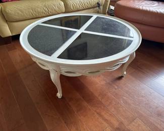 Oval coffee table with a white painted wooden frame and four-pane glass top divided by white muntins. Features curved cabriole legs and sits on a hardwood floor.