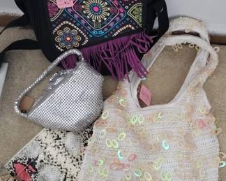 Collection of three handmade bags including a white mesh crocheted bag, a cream-colored embroidered bag with floral details, and a decorative patterned bag with purple fringe trim.