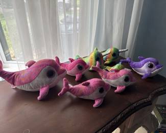 Set of colorful plush caterpillar toys in pink, purple, and yellow with segmented bodies and embroidered features. Appears to be vintage or collectible children's toys.