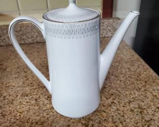 Tall white porcelain coffee pot with a blue decorative band around the rim and lid. Features a curved handle and appears to be vintage tableware.
