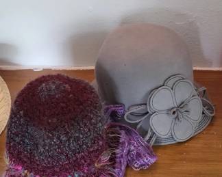Gray cloche-style hat with a black floral appliqué and purple tassel accent. The hat appears to be vintage or vintage-inspired with a structured crown.