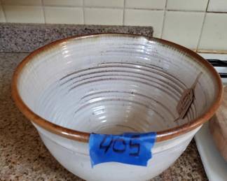 Large ceramic mixing bowl with a cream-colored interior and brown glazed rim. The bowl features concentric spiral lines in the interior and shows signs of age and use.