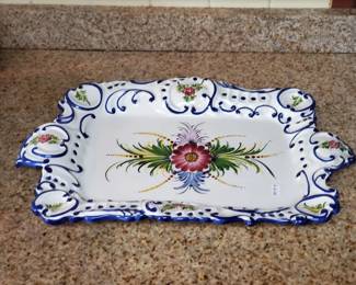 Hand-painted ceramic platter with blue and white scalloped border and floral center design. Features a pink flower with green foliage in the center and decorative blue scrollwork around the edges.