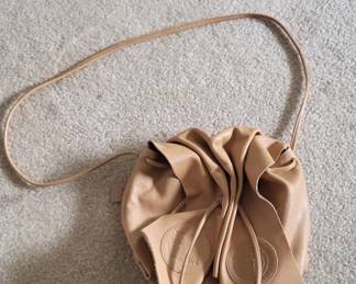 Small tan leather bag with gathered drawstring closure and adjustable shoulder strap. A simple, practical style suitable for casual carry.