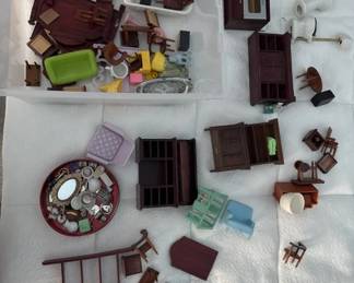 A collection of miniature dollhouse furnishings including wooden furniture pieces, decorative accessories, and small household items in various colors and styles. The lot appears to include chairs, tables, and other room décor typical of dollhouse sets.