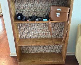 Simple wooden bookshelf with three adjustable shelves and patterned backing paper. Currently holds a few small items and boxes.