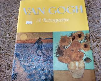 A comprehensive art book featuring Van Gogh's works with a yellow cover displaying reproductions of his famous paintings including a figure in a wheat field and sunflowers in a vase.