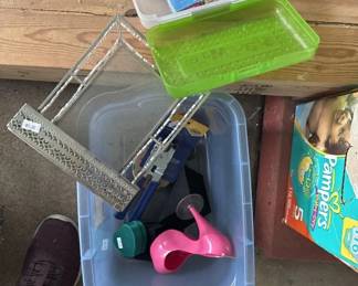 Plastic storage container filled with various cleaning tools and supplies including brushes, dustpans, and other household cleaning items.