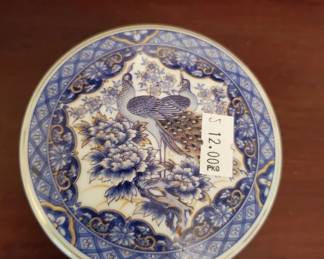 Round ceramic plate with blue and white underglaze decoration featuring a landscape scene with pagoda and foliage. The design is framed by a decorative blue border around the rim.