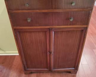 Wooden cabinet featuring two drawers at the top and two cabinet doors below, with vertical wood grain paneling on the doors. The piece appears to be mid-century in style with simple hardware and a warm wood finish.