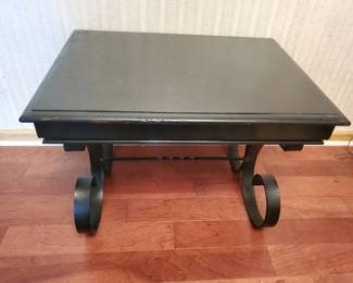 Low rectangular coffee table with a dark metal or painted top and curved metal legs fitted with casters for mobility. Simple industrial-style design.