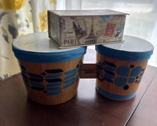 Set of three decorative storage boxes with Paris and travel-themed graphics in blue and brown tones. The cylindrical boxes feature vintage-style imagery and text.